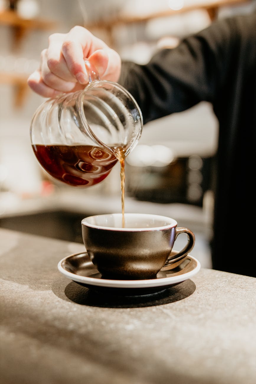 crop barista pouring hot coffee